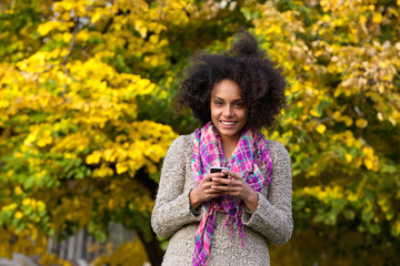 Smiling young woman holding mobile phone outdoors