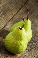 Two fresh green pear with drops of water on wooden table, select