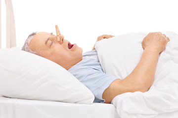 Senior sleeping with a clothespin on his nose