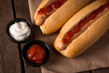Two hot dogs with ketchup on wooden background