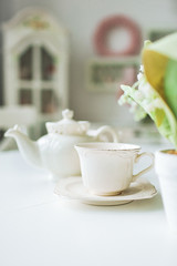 Fine tea cup and kettle on white table in kitchen