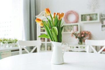 Fototapeta na wymiar Beautiful orange flowers in vase on rustic kitchen table