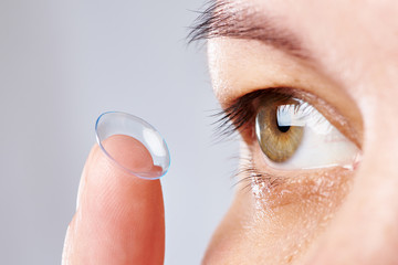 Young womans eye and contact lens - obrazy, fototapety, plakaty