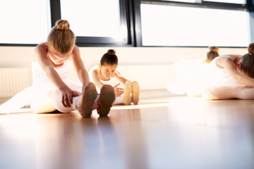 Obraz premium Ballet Girls Doing Sit and Reach Warm up Exercise