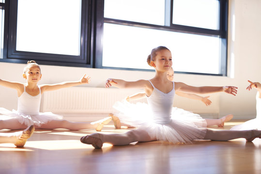 Sitting Young Ballerinas Stretching Arms and Legs