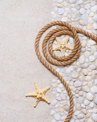 Fototapeta na wymiar Rope and starfish on the sea pebbles