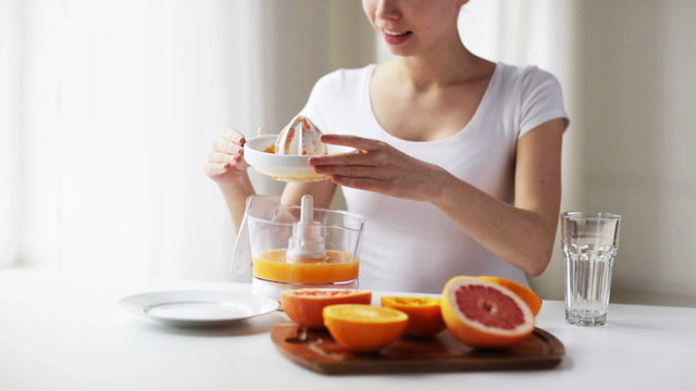 woman with squeezer pouring orange juice to glass