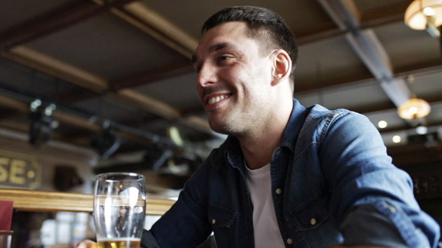 happy young man drinking beer at bar or pub