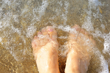 Fototapeta premium Female legs in the waves of the surf