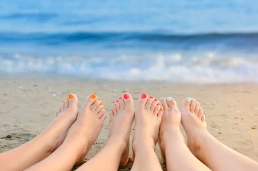 Wall murals Pedicure Female legs with color pedicure on the background of the sea