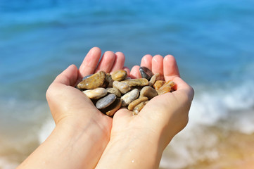 Handful of stones in hands, against sea