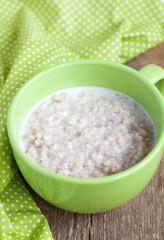 Green buckwheat porridge with milk on wooden table