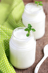 Homemade yogurt in two small glass jars on a wooden table 