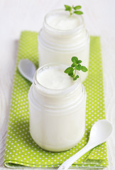 Obraz na płótnie Canvas Homemade yogurt in two small glass jars on a wooden table 