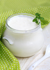 Homemade yogurt in small glass jar on a wooden table 