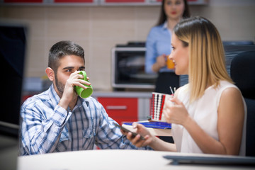 Two young people drinking coffee in an office