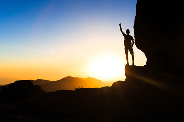 Man hiking climbing silhouette success in mountains sunset