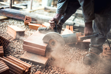 worker using an grinder for cutting construction bricks