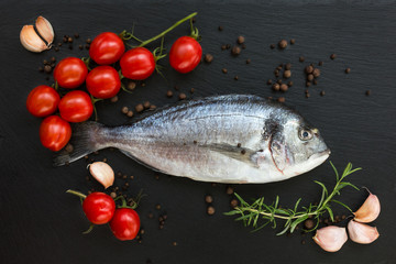 Dorado fish on slate board, cherry tomatoes, rosemary, garlic