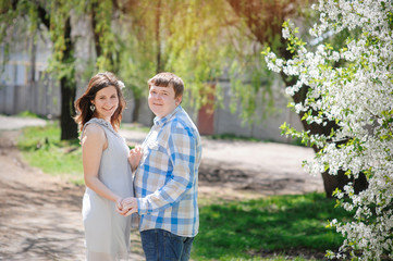 Fototapeta premium beautiful newlyweds walking in spring blooming garden