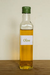 Olivenöl- Flasche auf einem Holzbrett