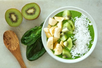 Green smoothie bowl with spinach, bananas, kiwi and coconut