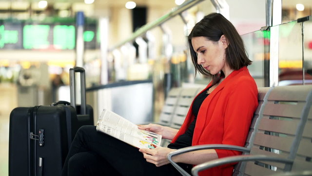 Young woman reading magazine while sitting at train station
