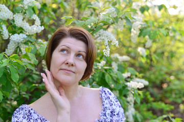  adult woman near blossoming bird cherry in the park