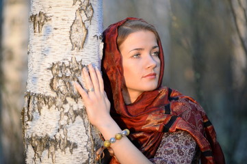 Russian girl in a scarf in a birch forest, close-up 