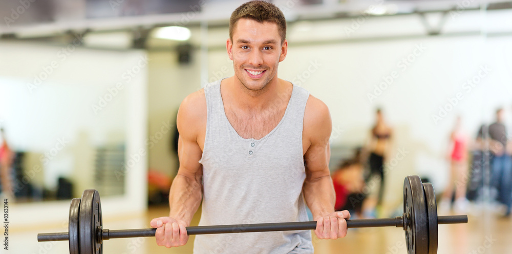 Wall mural smiling man with barbell in gym