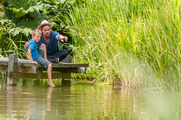 On a wood pontoon, father teaching his young son to respect nature