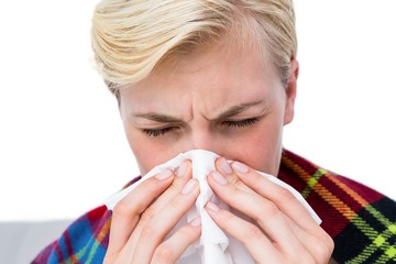 Sick blonde woman blowing her nose 