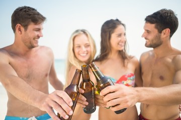 group of friends in swimsuits cheering with beers