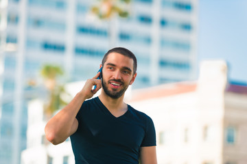 Handsome happy and casual young man with cellphone talking