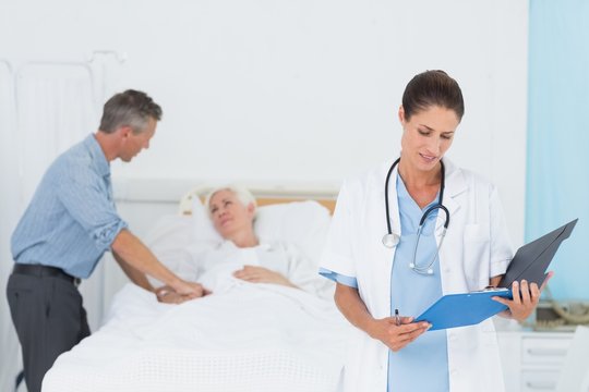 Doctor explaining report to female patient and husband