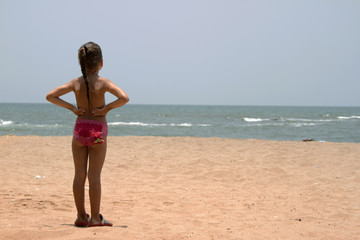 Beautiful little girl standing on the sandy beach. India, Goa