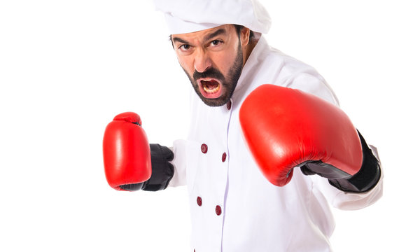 Chef fighting with boxing gloves over white background