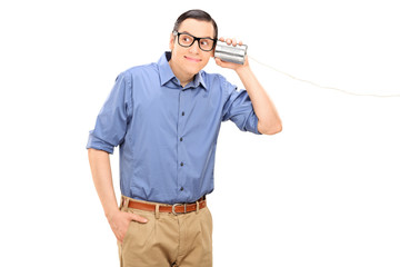 Cheerful young man talking through a tin can phone