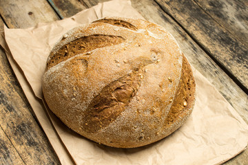 Loaf of fresh baked wheat bread on wooden table