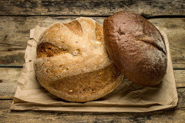 Loafs of bread on paper bag at wooden background