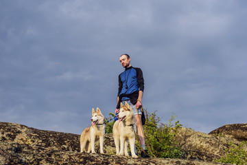 young caucasian male hiking with huskies in mountains