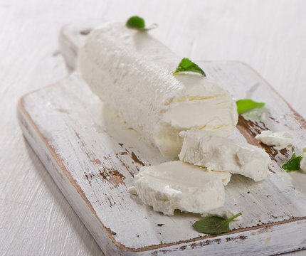 Goat cheese with herbs on  white wooden table