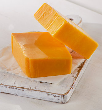 Cheddar Cheese on a white wooden Cutting Board.