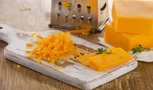 Grated Cheddar Cheese on  wooden Board.