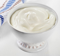 Greek yogurt in a white bowl   on  white wooden table