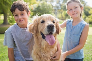 Smiling sibling with their dog in the park