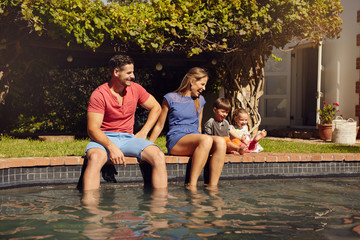Fototapeta na wymiar Happy young family enjoying near pool