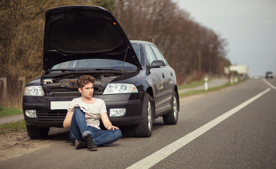 Upset man checking his car engine after breaking down 