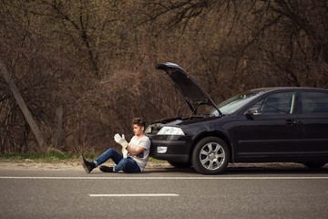 Upset man checking his car engine after breaking down 