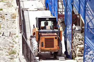 Fototapeta na wymiar Orange lifting truck on a building site with metal scaffoldings